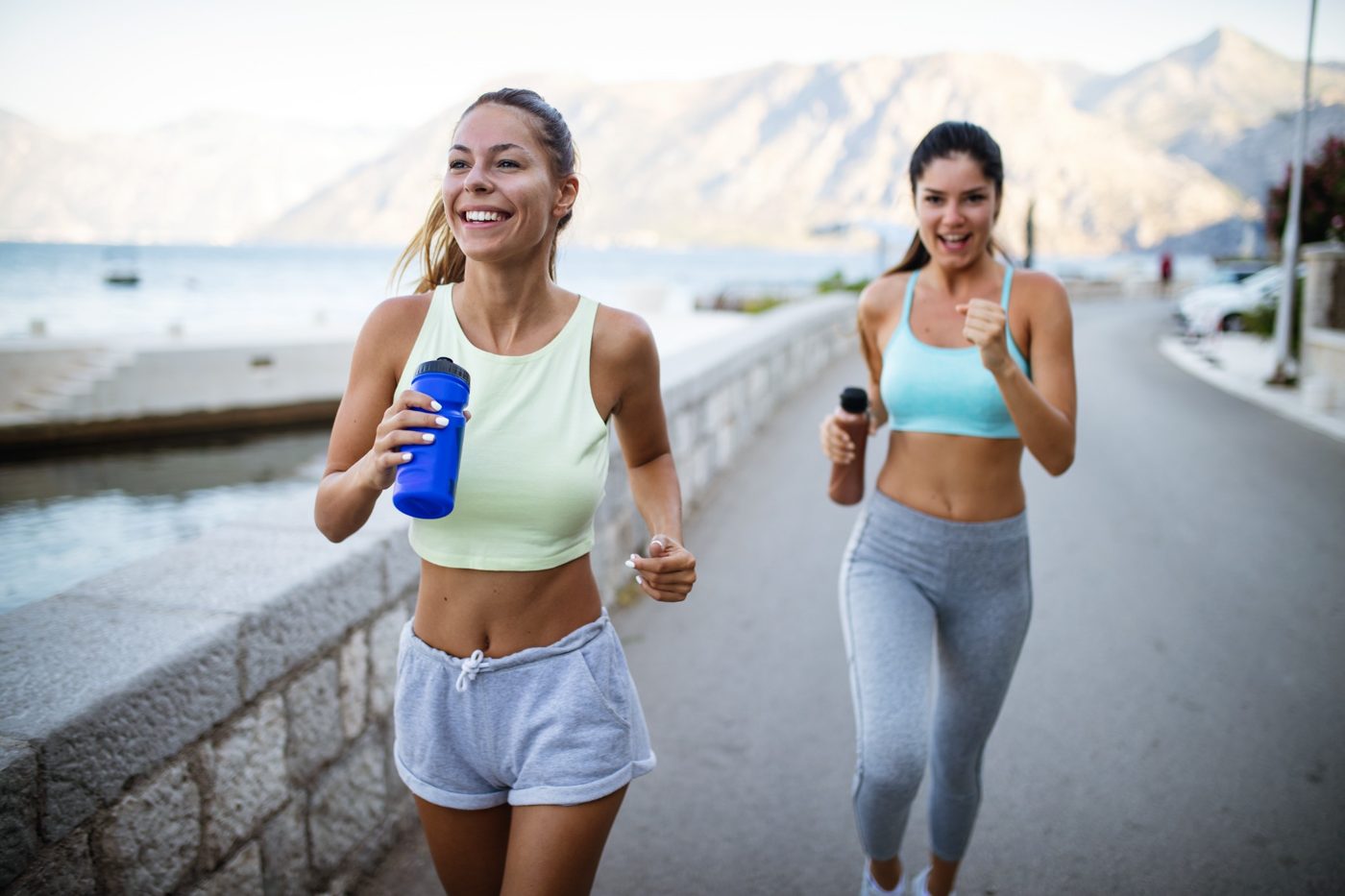 Two women jogging together beside the water